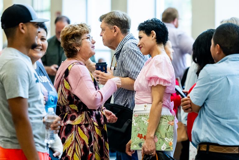 A diverse group of people engaging in conversation at an indoor gathering.
