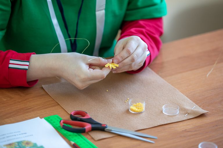 Craftsperson creating detailed bead jewelry with care and precision, showcasing handmade artistry.